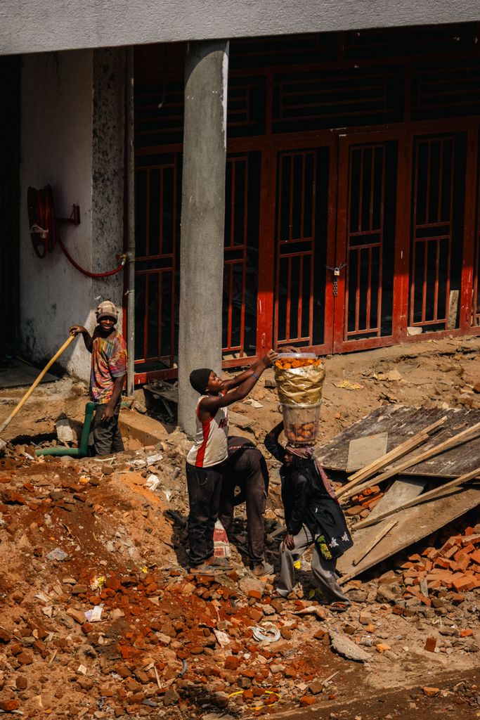 A group of construction workers engaged in manual labor on a city building site.
