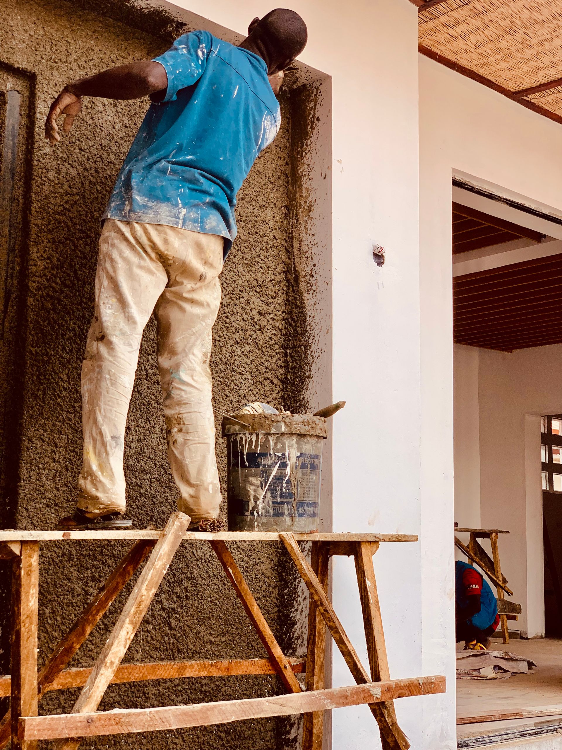 Hardworking construction worker plastering a wall in Kaduna, Nigeria.